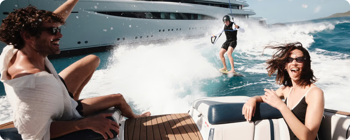 Guests enjoying the sea from a luxury yacht — wakeboarding near the vessel